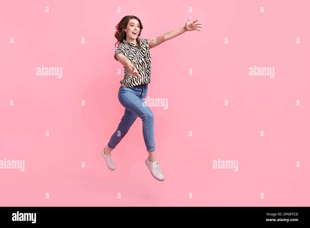 Full length profile portrait of overjoyed carefree person jump rush raise opened arms empty space isolated on pink color background Stock Photo