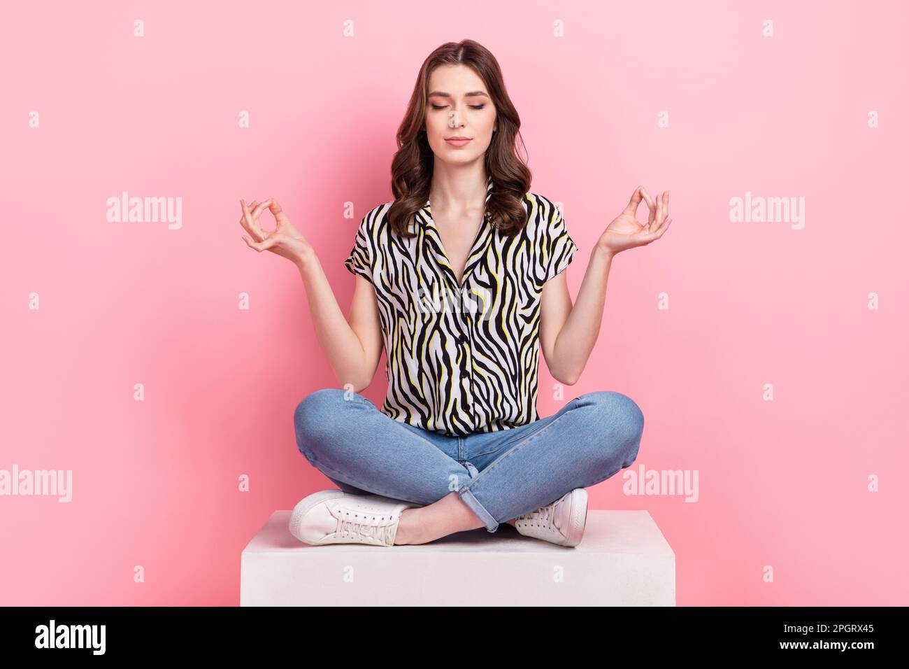 Full size photo of peaceful pretty girl sit podium crossed legs meditate isolated on pink color background Stock Photo