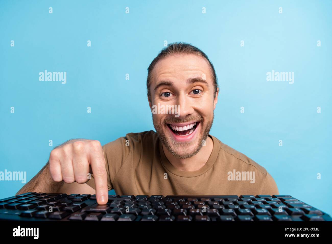 Photo of positive excited guy dressed beige t-shirt typing keyboard communicating modern device isolated blue color background Stock Photo