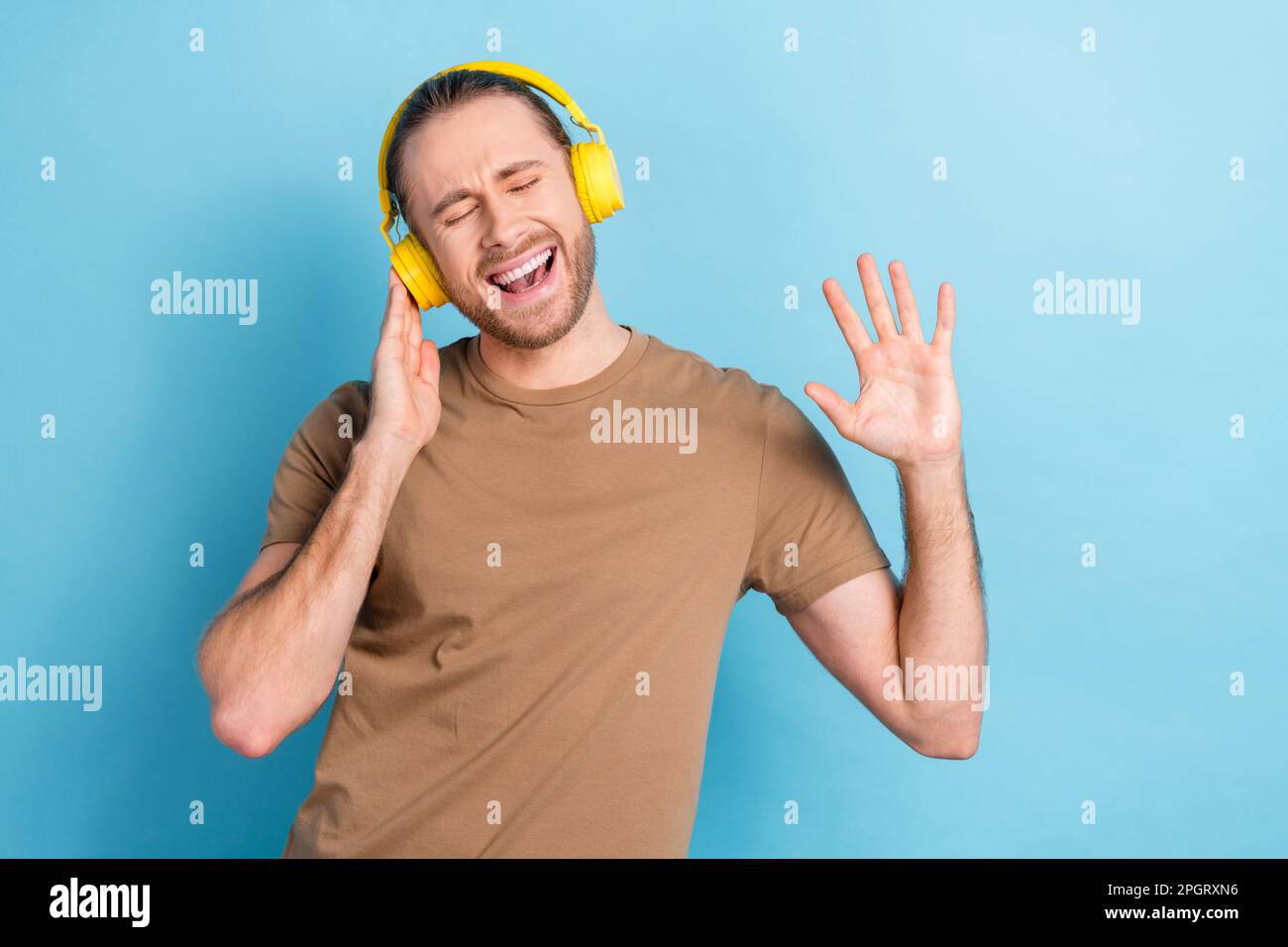 Photo of funny funky man wear beige t-shirt earphones listening songs singing isolated blue color background Stock Photo