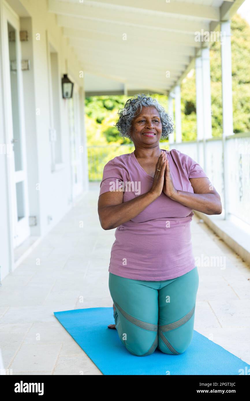 African american senior woman smiling and meditating in prayer pose while  kneeling on mat in balcony. Copy space, unaltered, lifestyle, retirement,  yo Stock Photo - Alamy