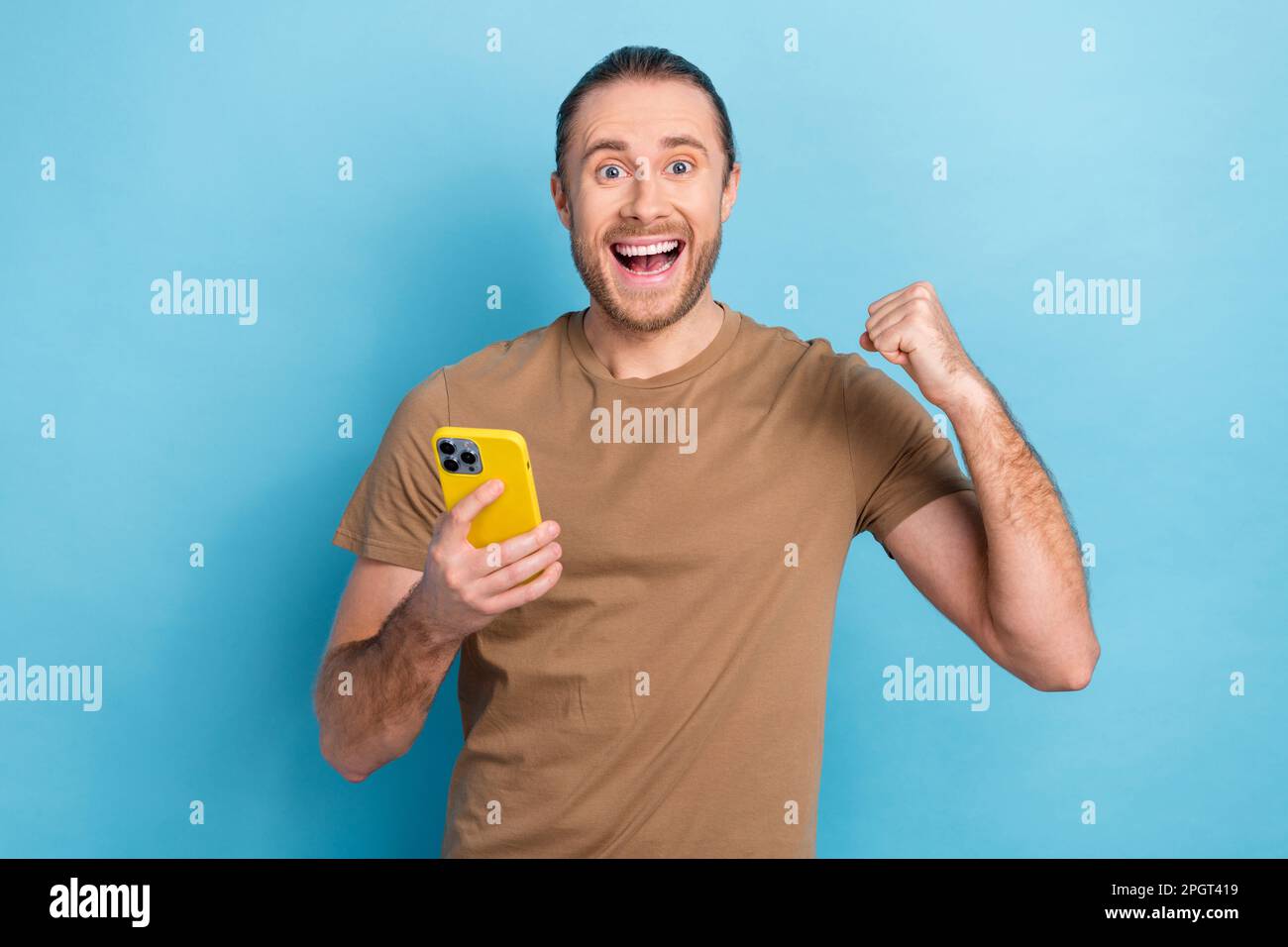 Photo of excited funny winner lottery online gambling phone internet parimatch fist up celebrate million jackpot isolated on blue color background Stock Photo