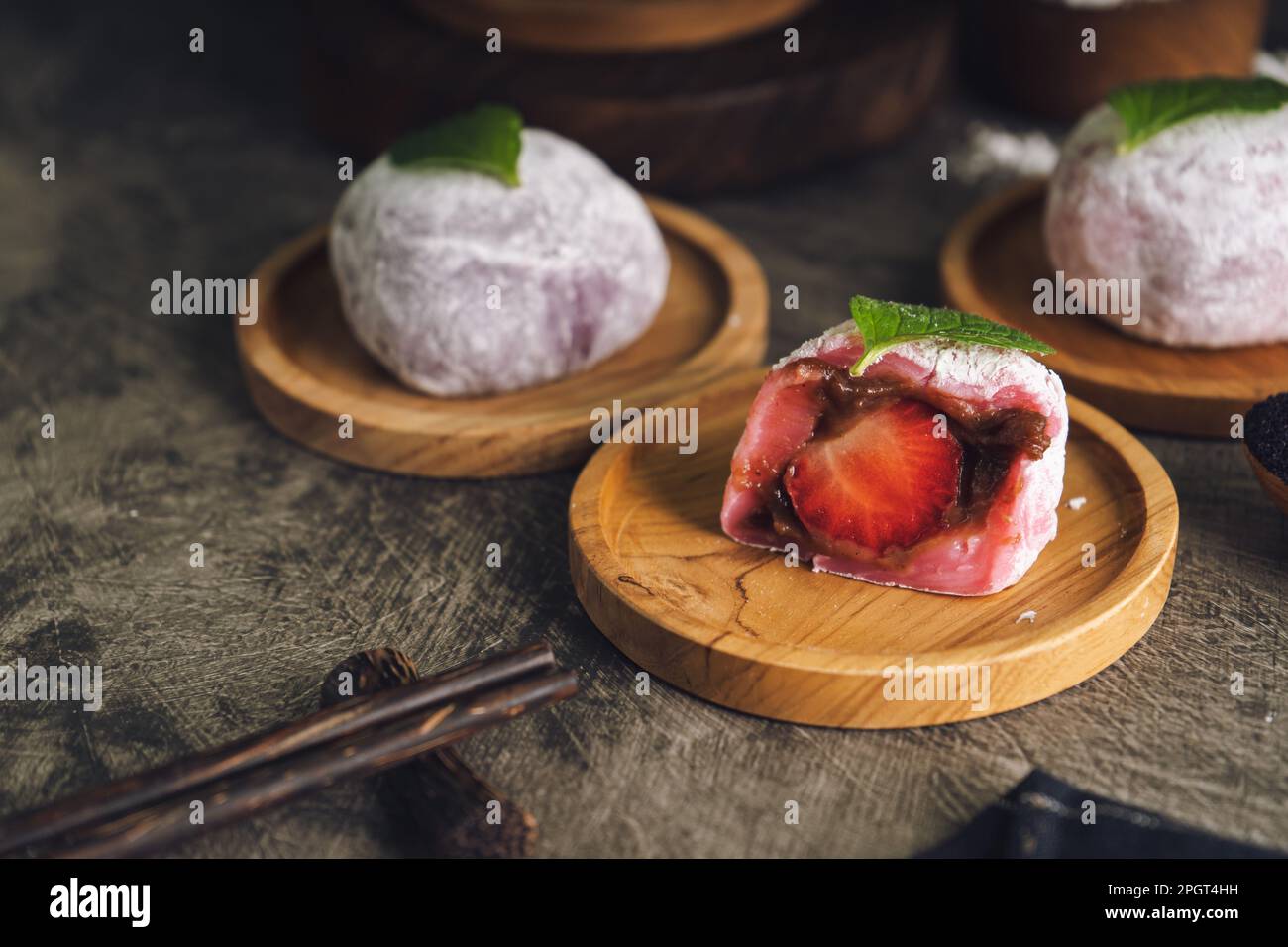 Japanese mochi or rice cake filled with red bean and strawberry, mint leaves on top. Japan traditional rice cake. Stock Photo