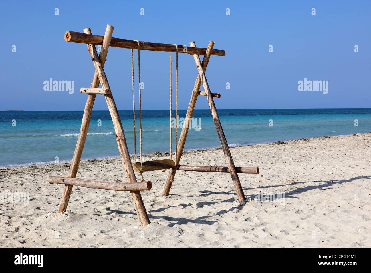 Wooden swing on a sand against the blue sea. Beach holidays on resort Stock Photo