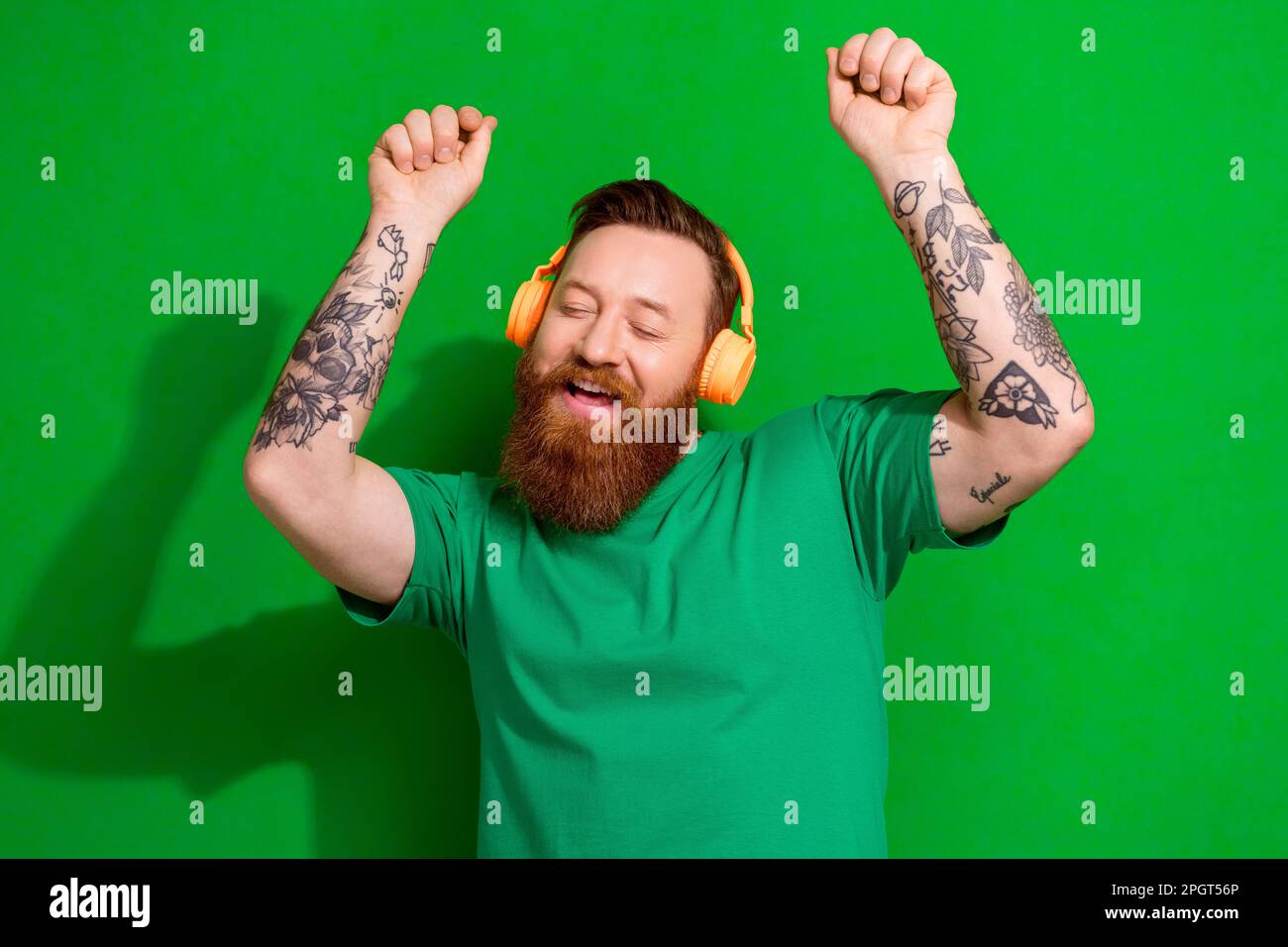 Photo of cheerful dreamy man wear t-shirt listening songs headphones having fun isolated green color background Stock Photo
