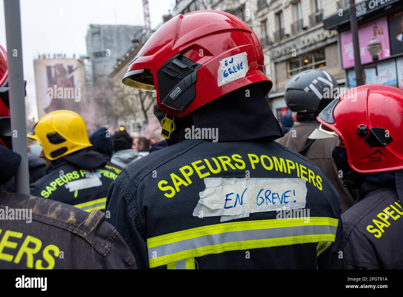 Striking French firefighters in fire gear seen from behind during a protest against the retirement reform in France Stock Photo