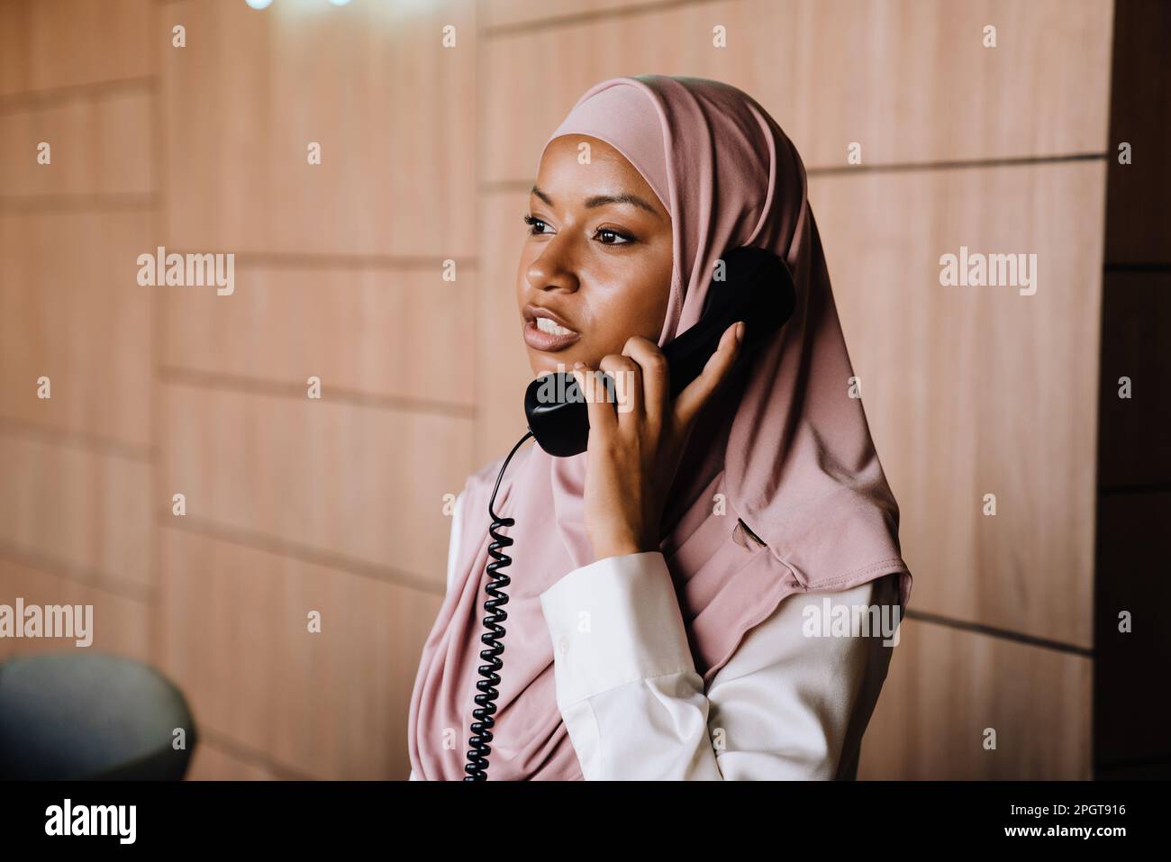 Muslim young businesswoman talking on phone while working at reception Stock Photo