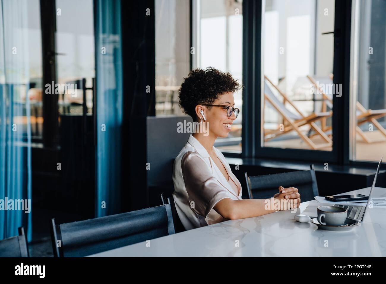 Middle-aged businesswoman smiling while working on laptop in office Stock Photo