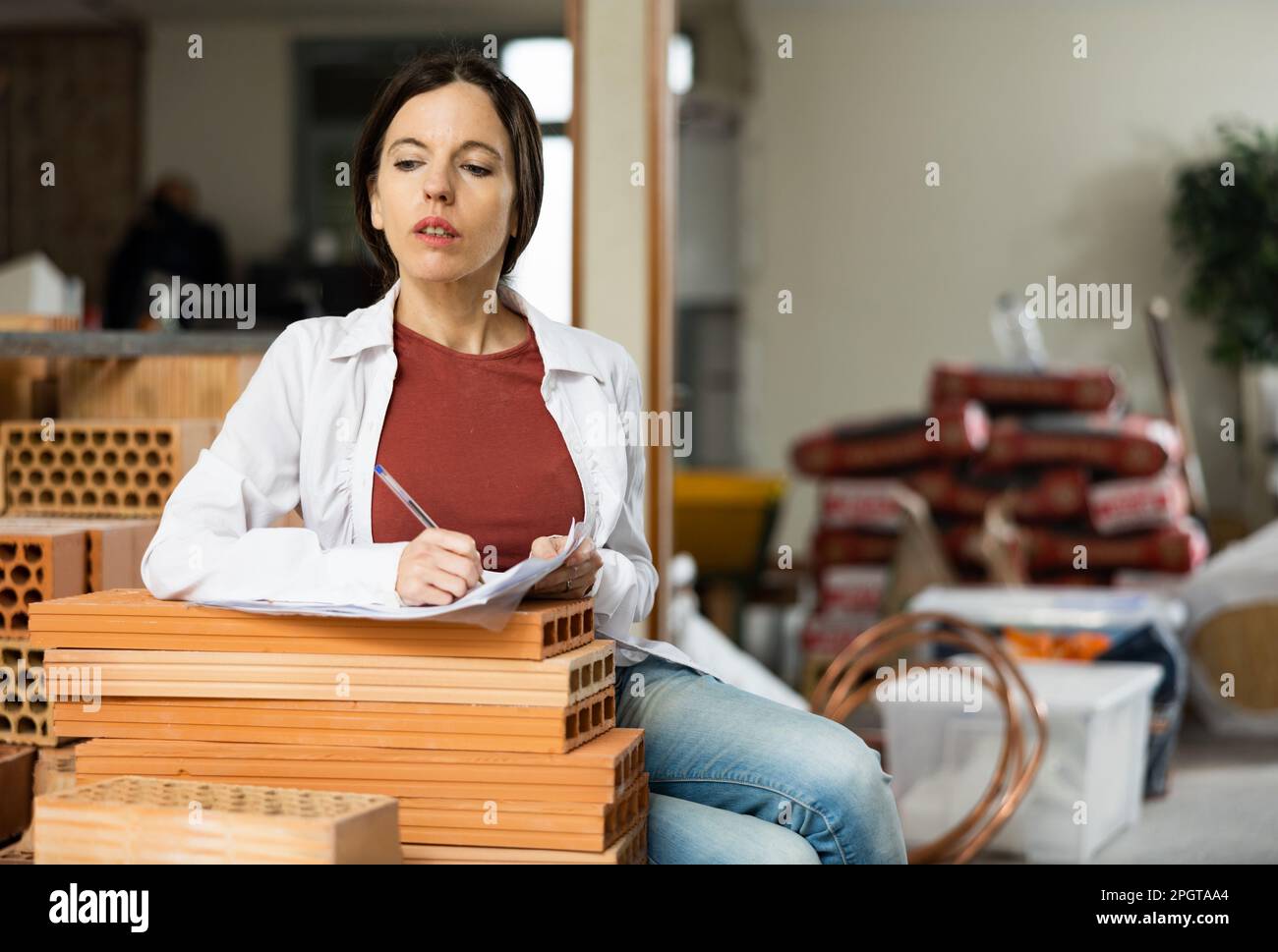 Interested brunette making notes while planning home renovation Stock Photo
