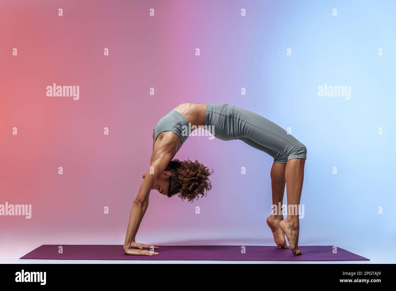 Sporty woman doing stretching exercises on yoga mat on studio