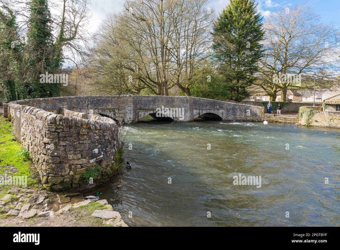 Old stone bridge over the River Wye in the pretty Derbyshire village of Ashford in the Water in the Peak District Stock Photo