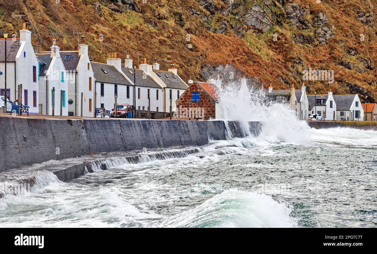 Pennan village Aberdeenshire Scotland a very high tide and a large waves crashing onto the seawall in front of the houses Stock Photo