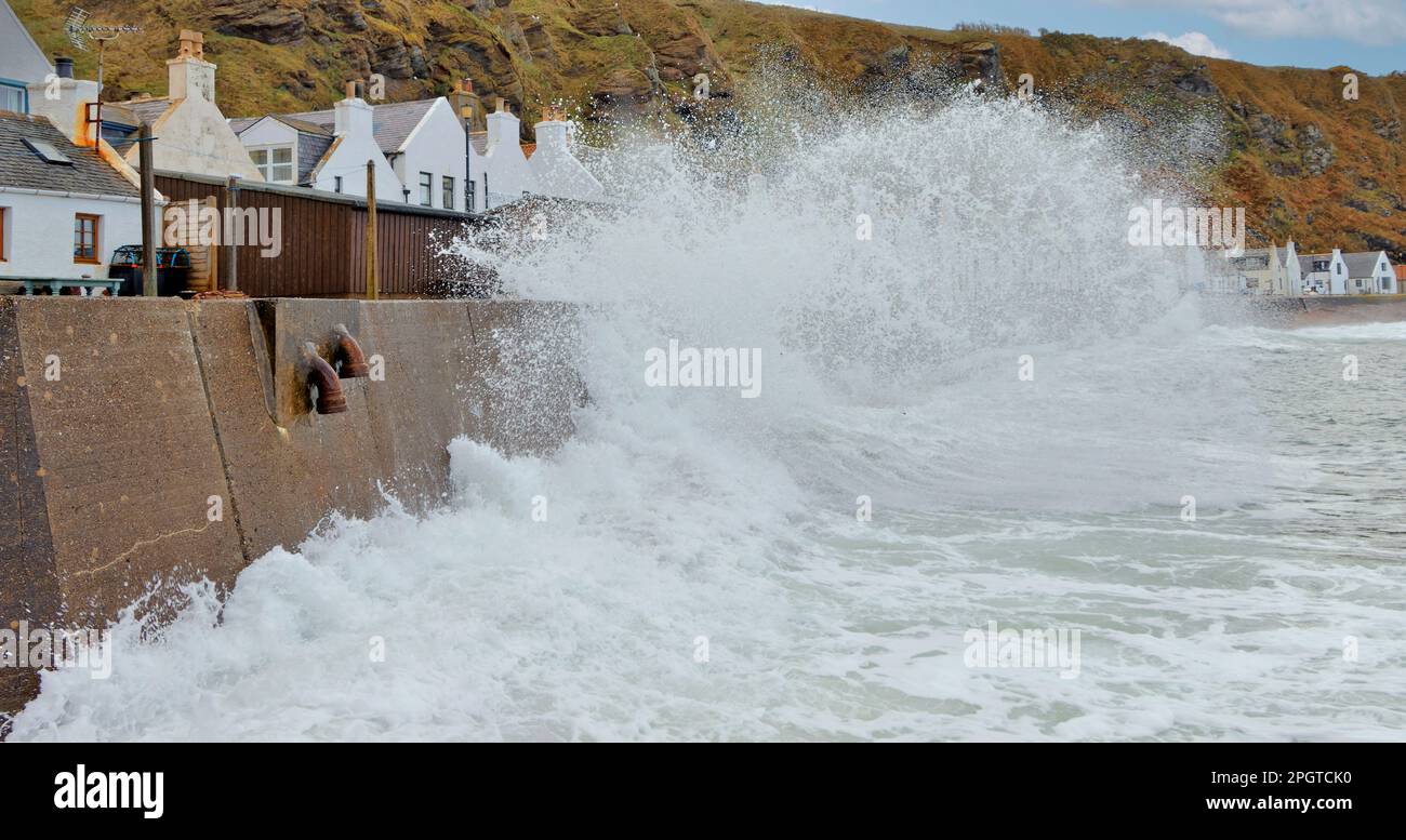 Pennan village Aberdeenshire Scotland very high tide and huge waves and foam crashing onto the seawall in front of the houses Stock Photo