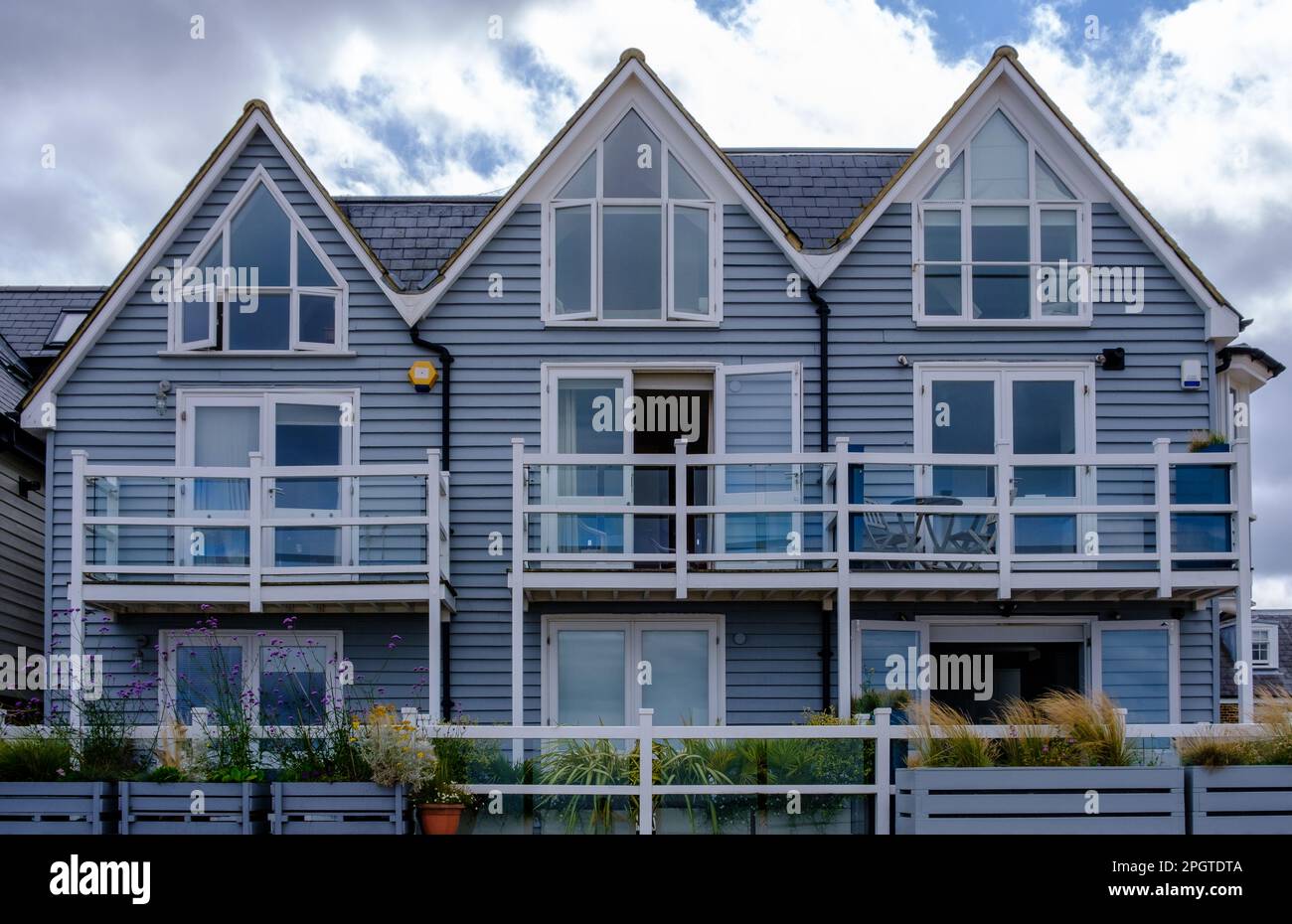 Old shingled terraced houses with balconies and foliage on Whitstable