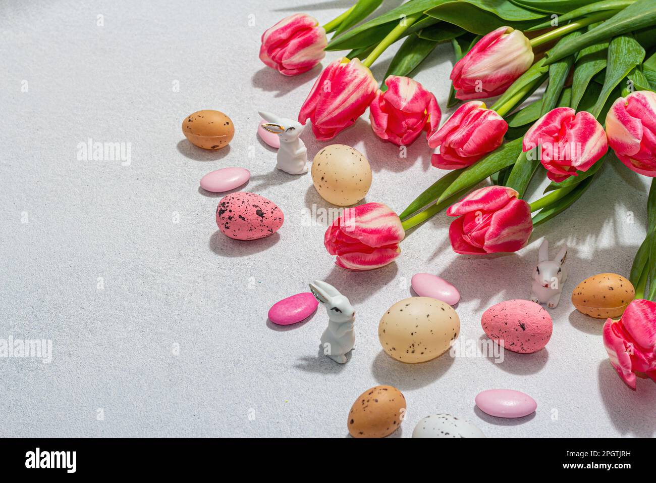 Pink tulips with Easter eggs and rabbits on light stone concrete ...