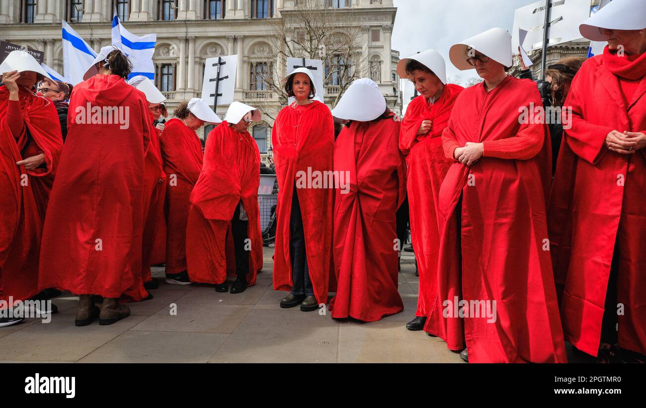 London, UK. 24th Mar, 2023. The handmaidens stop by the Women of WWII memorial to pay their respects, then join the Israeli protest. A group of circa 40 women in handmaiden outfits rally for women's rights and against the Netanyahu leadership. Hundreds of demonstrators protest against Israeli Prime Minister Benjamin Netanyahu during his visit to the UK today. Both those rallying for the rights of Palestinians, and those protesting about changes to the judiciary proposed by Netanyahu's government make their voices heard loudly. Credit: Imageplotter/Alamy Live News Stock Photo