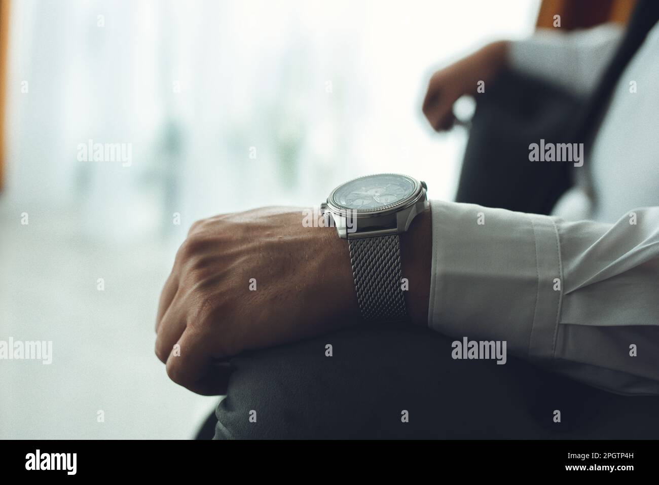 A man seated in a chair, wearing a white shirt, tie, and watch Stock ...