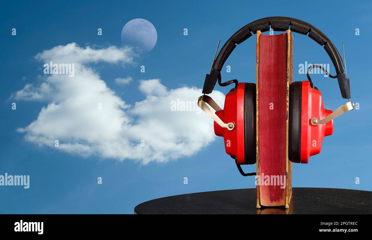 audio book and vintage headphone in front,sky background, cloud and rising moon. Stock Photo