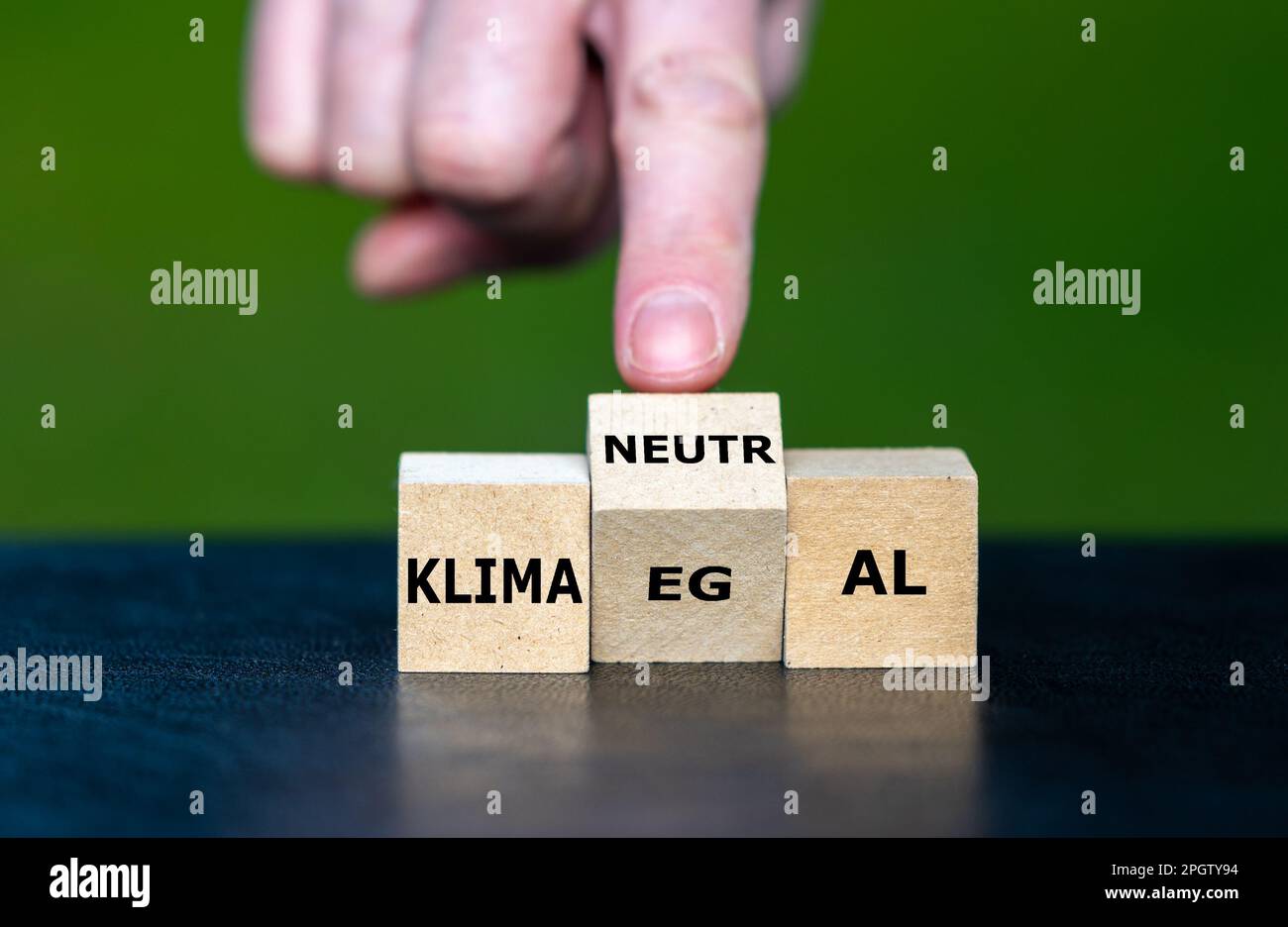 Hand turns wooden cube and changes the German expression 'klima egal' (climate I do not care) to 'klimaneutral' (climate neutral). Stock Photo