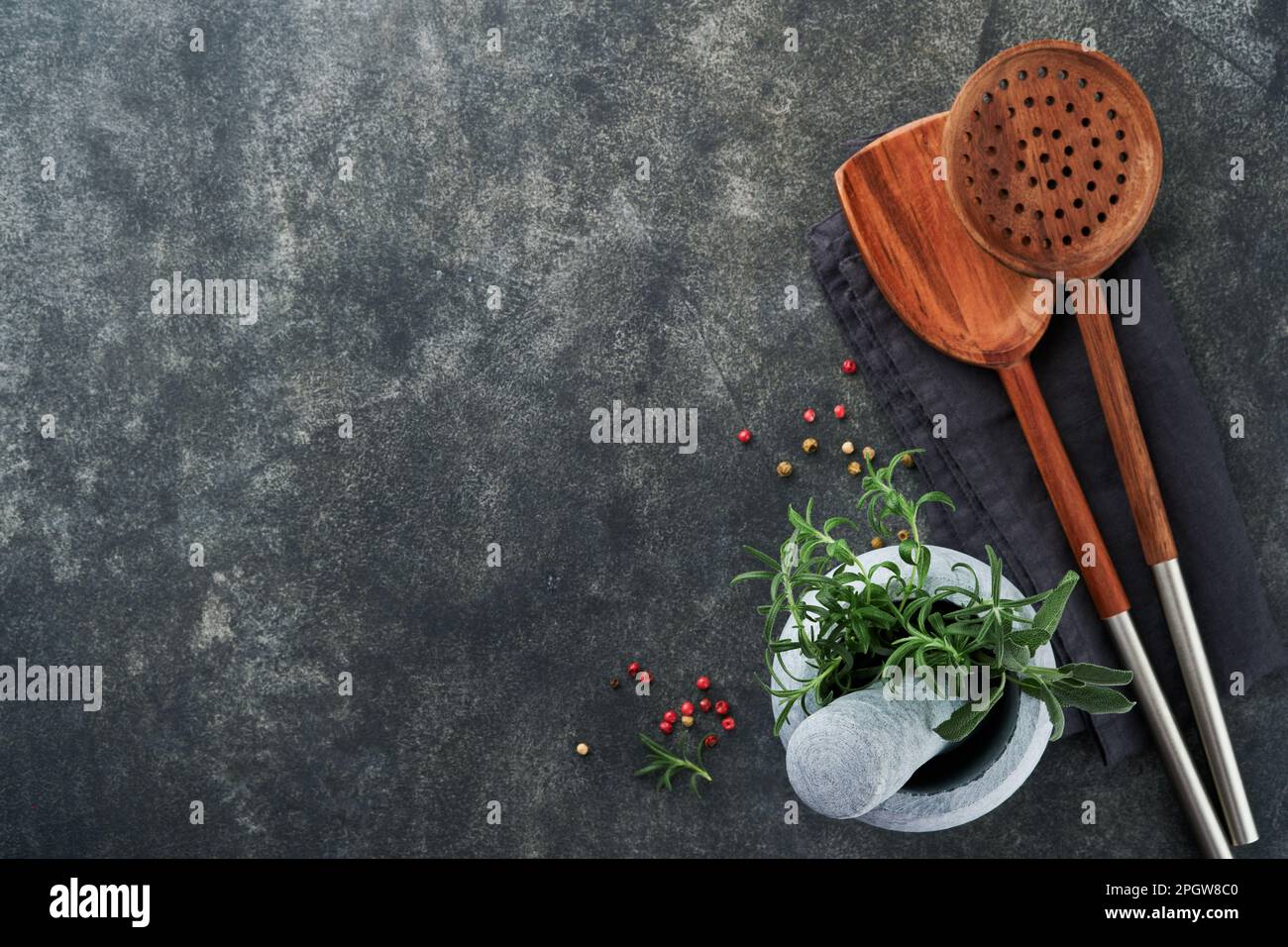 Fresh Rosemary and saffron in marble mortar and wooden spoons on black stone background. Food