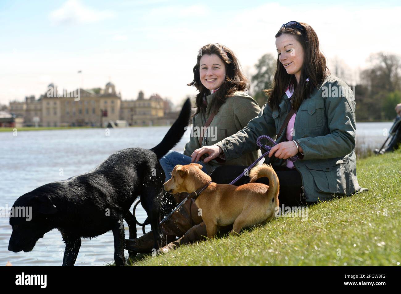Young women with their dogs by the lake at The Badminton Horse Trials in Gloucestershire, UK. Stock Photo