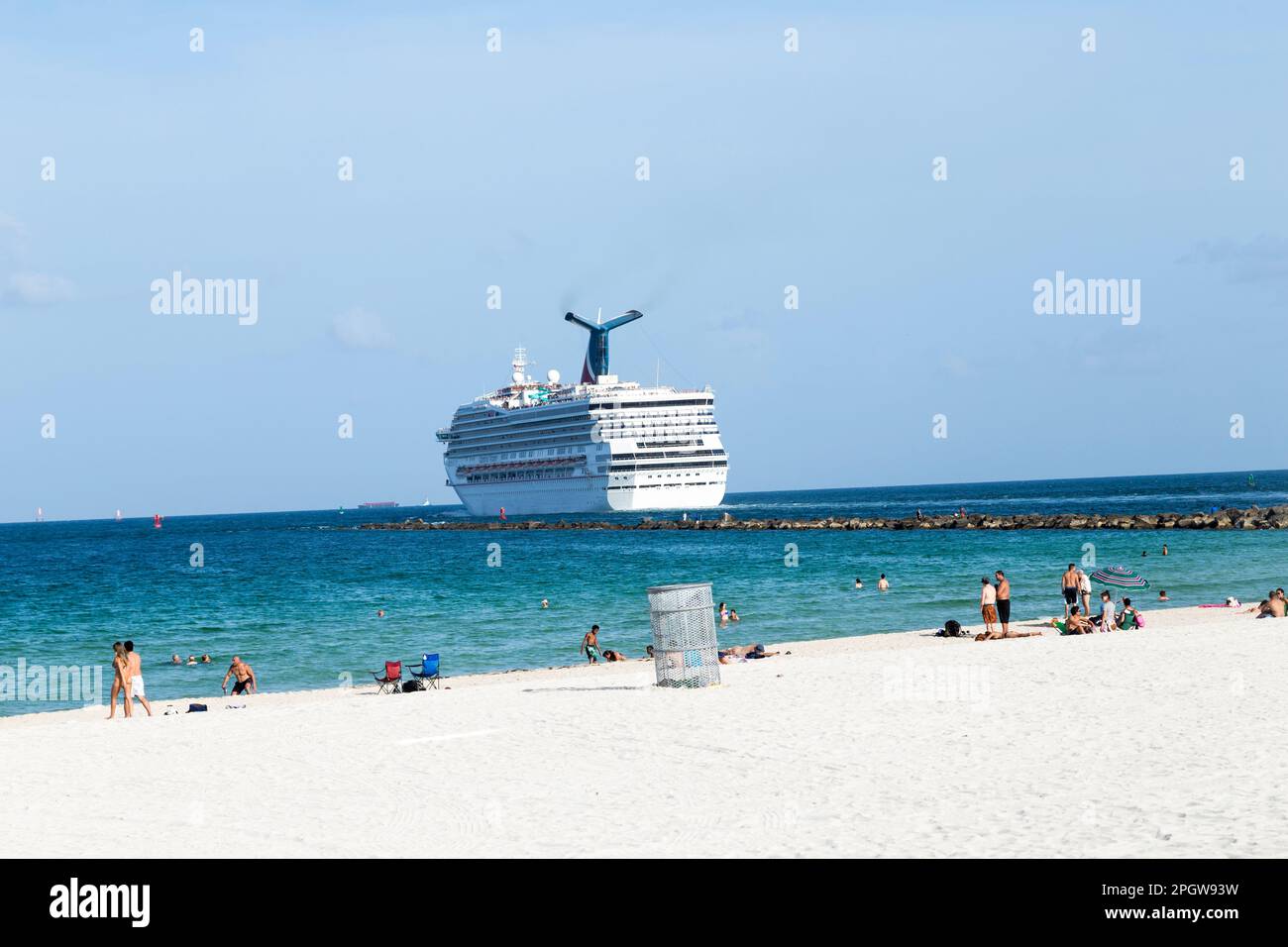 Miami, USA - August 18, 2014: People enjoying the beach next to the cruise ship Carnival victory leaving Miami harbor to the Carribean. Stock Photo