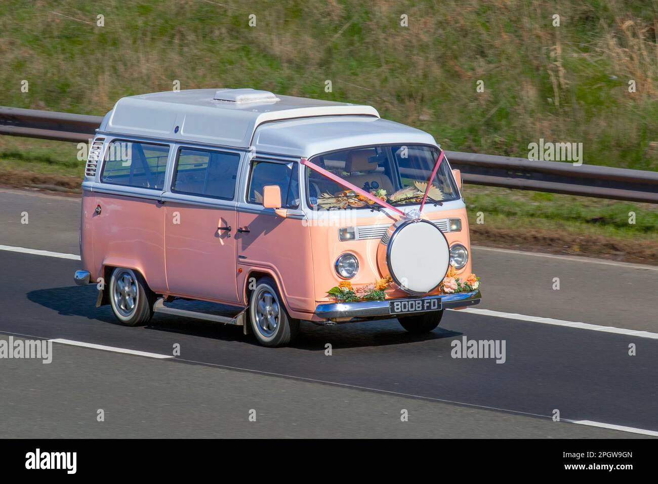 1976 70 seventies Pink VW VOLKSWAGEN 'Flower Power' Delivery Van, conversion Wedding car, with ribbons floral decoration and dashboard flowers; travelling on the M61 motorway UK Stock Photo