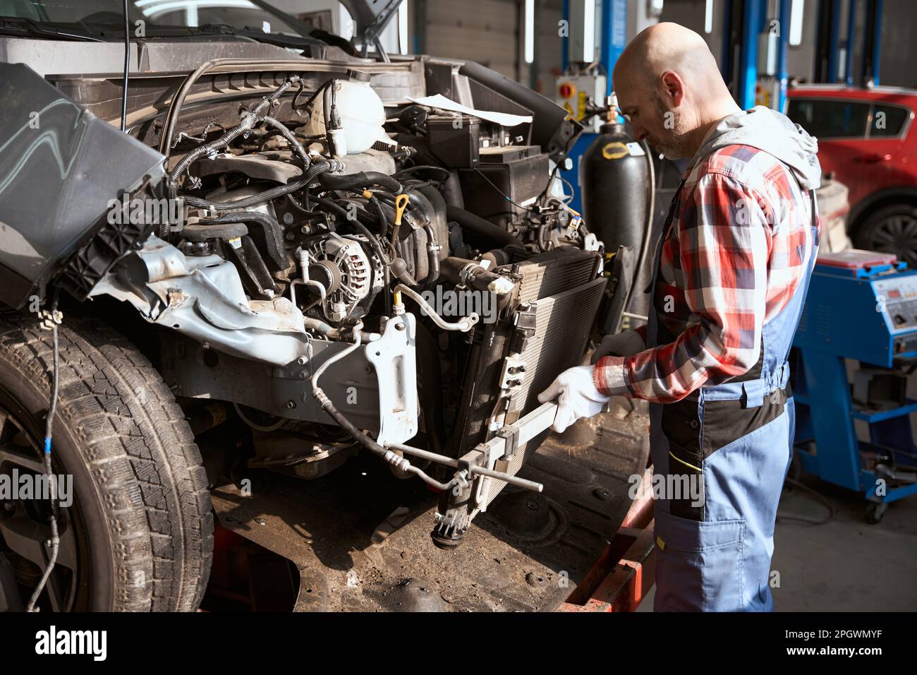 Middle-aged auto repairman stands in front of a disassembled car Stock Photo