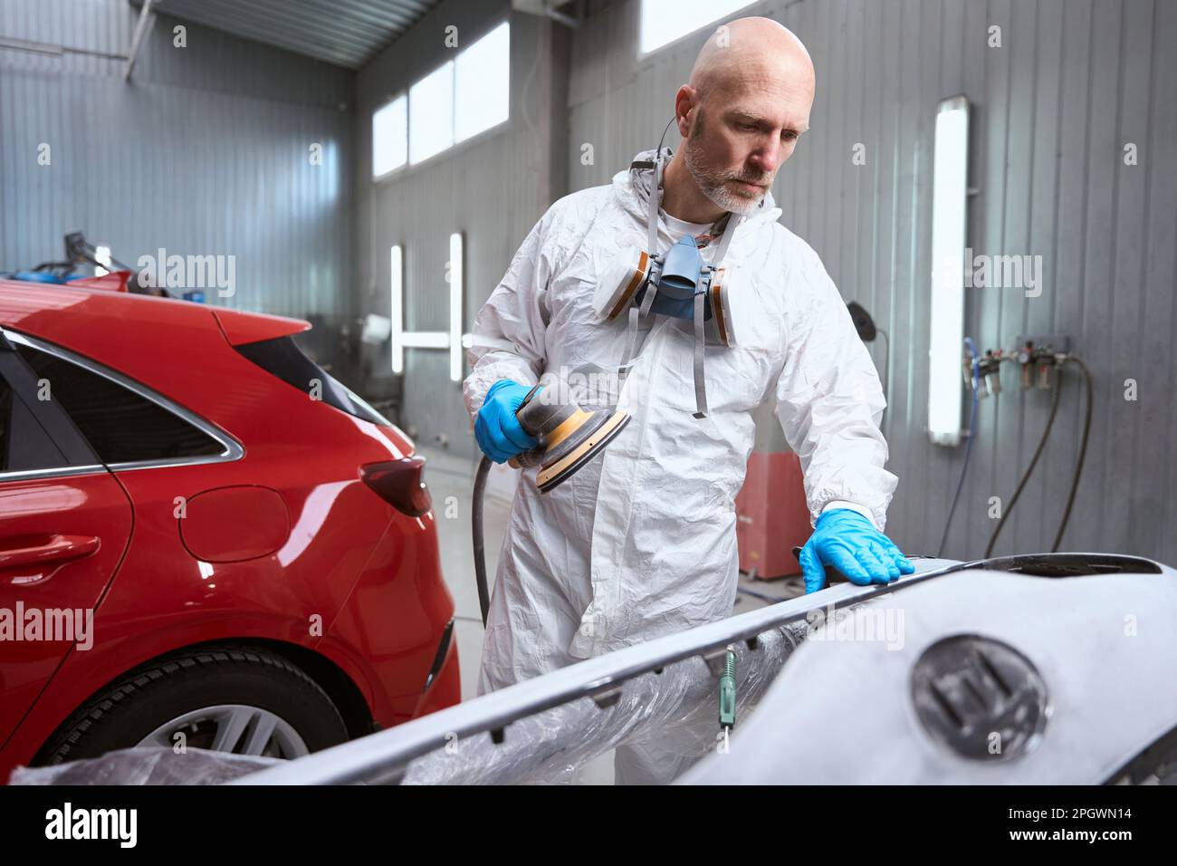 Auto repair shop employee works with unpainted car bumper Stock Photo