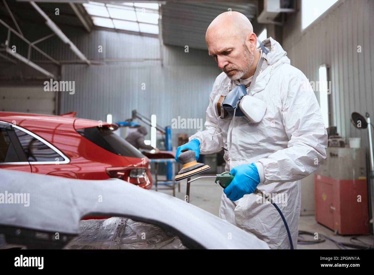 Auto repairman uses a pneumatic tool in process of grinding Stock Photo