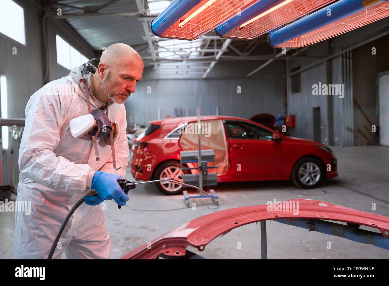 Experienced craftsman in overalls selects paint for a car Stock Photo
