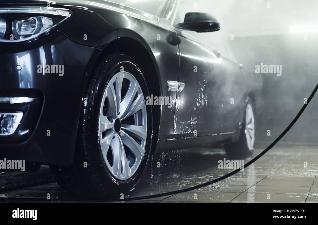 High pressured water. Modern black automobile get cleaned inside of car