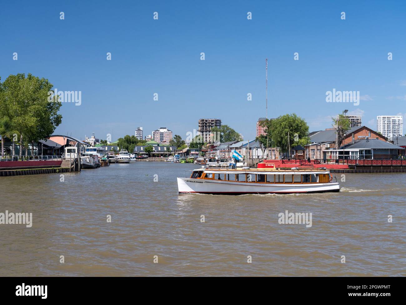 Tigre, Argentina - 7 February 2023: Tourist tour boat or cruise passes ships docked in the port of Tigre on Parana delta Stock Photo