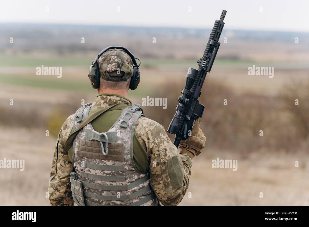 The Soldier Is Standing In Complete Military Uniform With Gun And