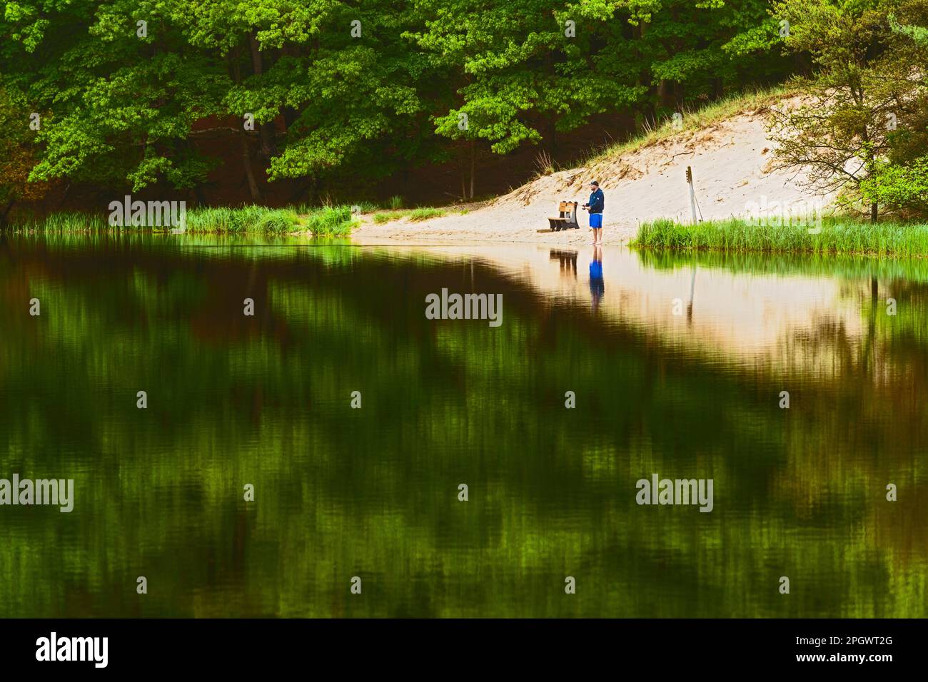 Fisherman and reflection on Hamlin Lake in Ludington State Park near