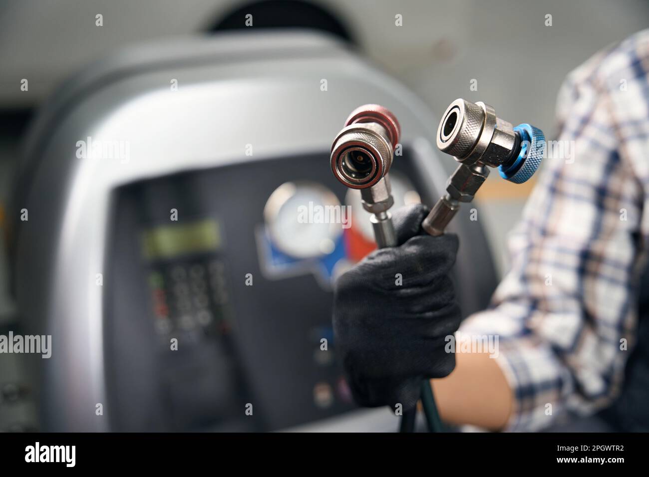 Master holds hoses from special flushing system for car air conditioner