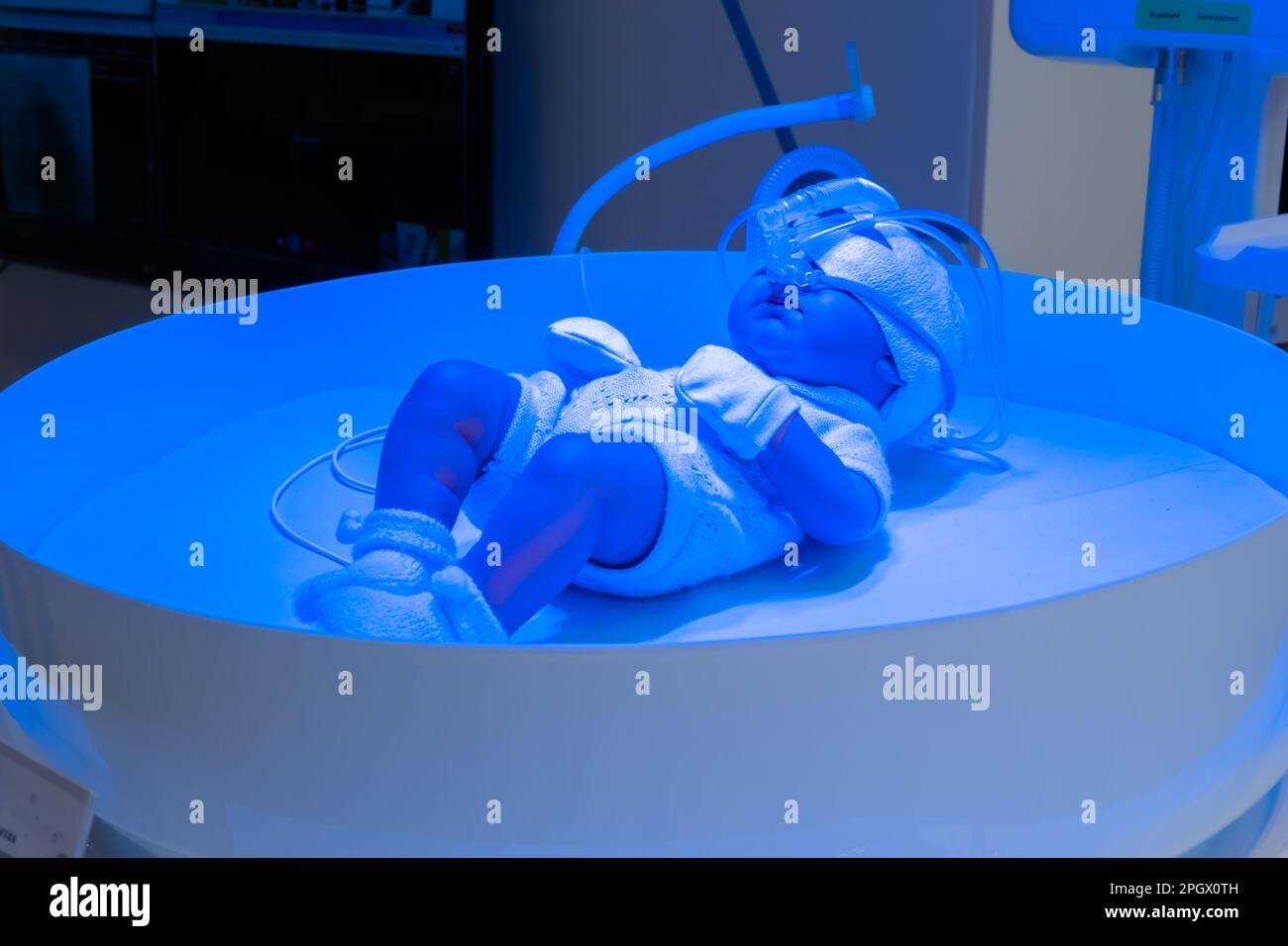 Newborn mannequin lying under blue uv light in neonatal bed Stock Photo