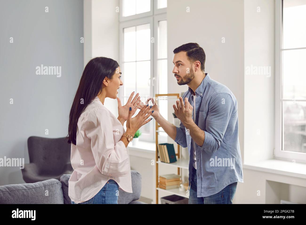 Young couple standing at home and arguing in the living room. Quarrel and divorce concept. Stock Photo