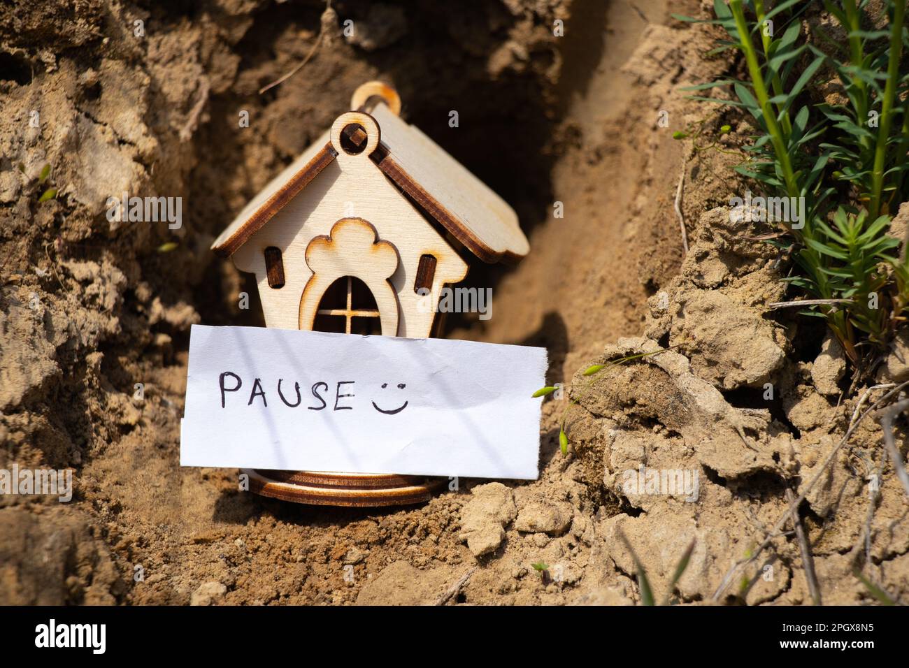 a wooden house stands on the ground in the sun and next to it is an inscription in English pause Stock Photo