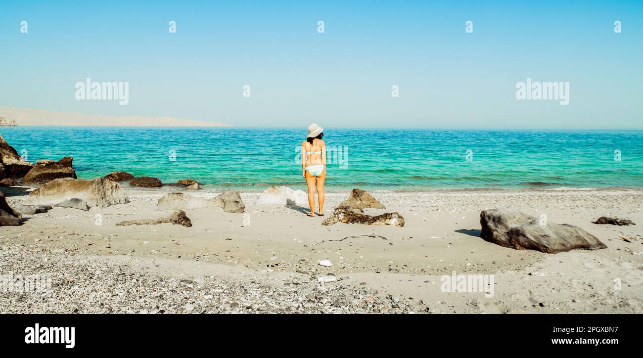 Panorama tourist woman in bikini stand on white sand beach alone on