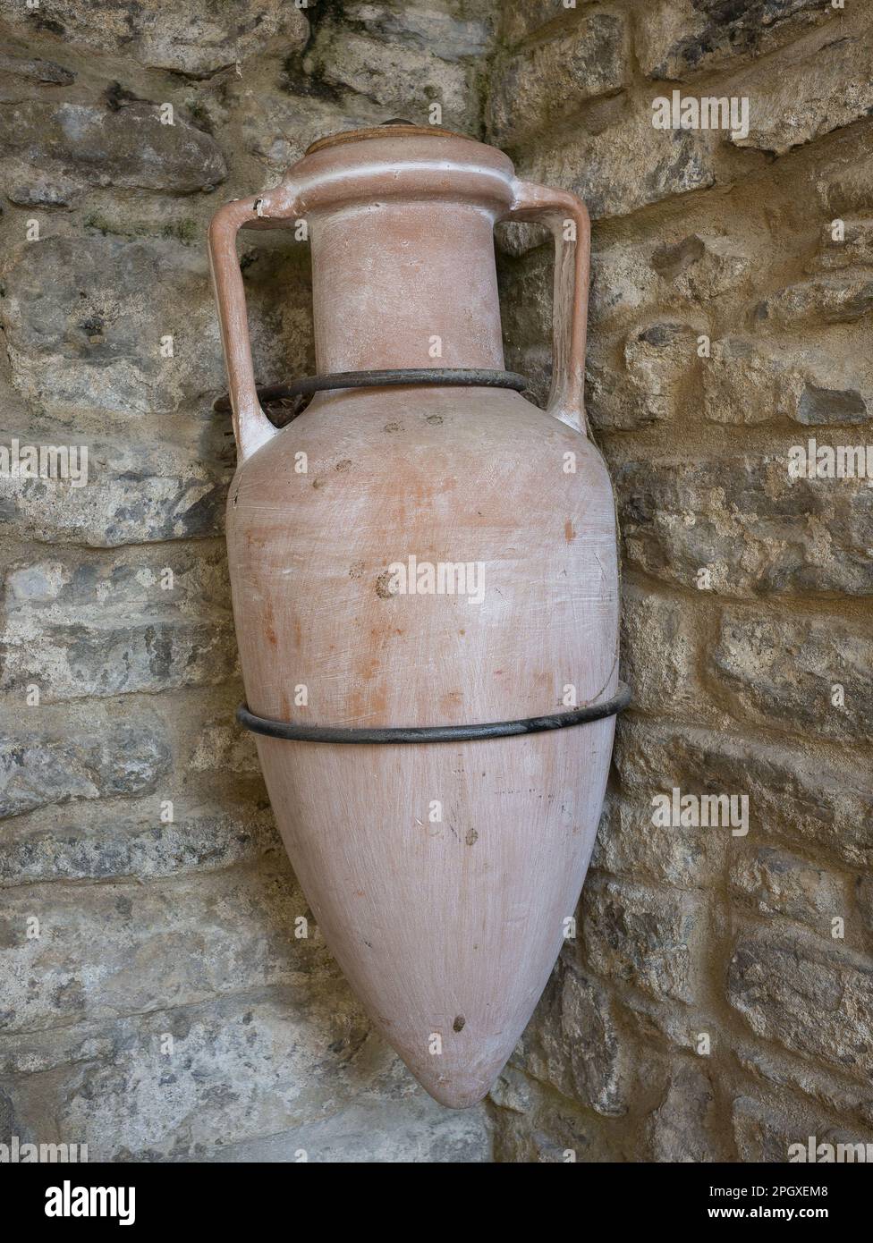 ancient Roman amphora hanging on a stone wall for decorative purposes Stock Photo