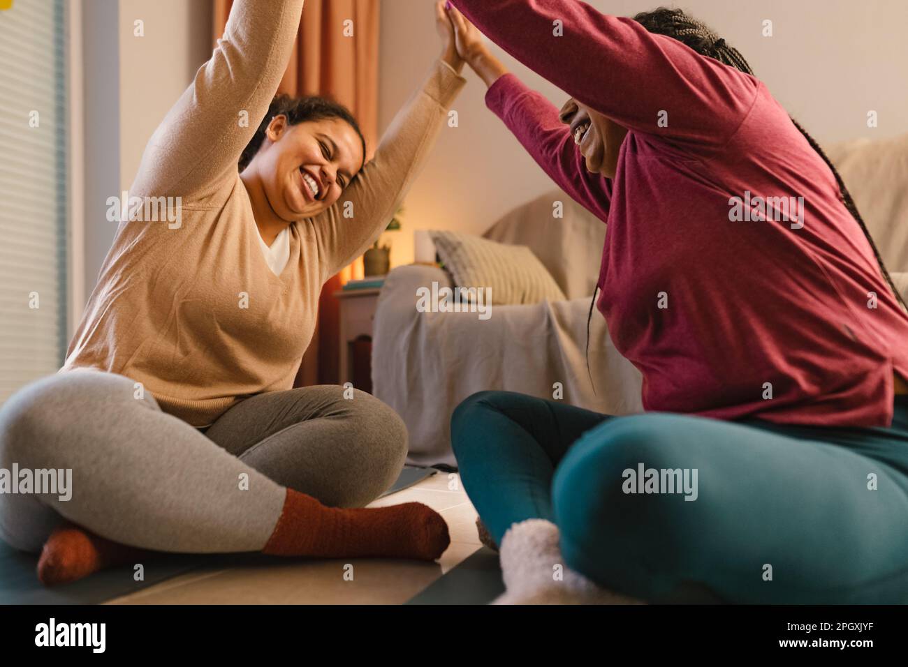 Happy young daughter with her mother having fun doing yoga at home Stock Photo