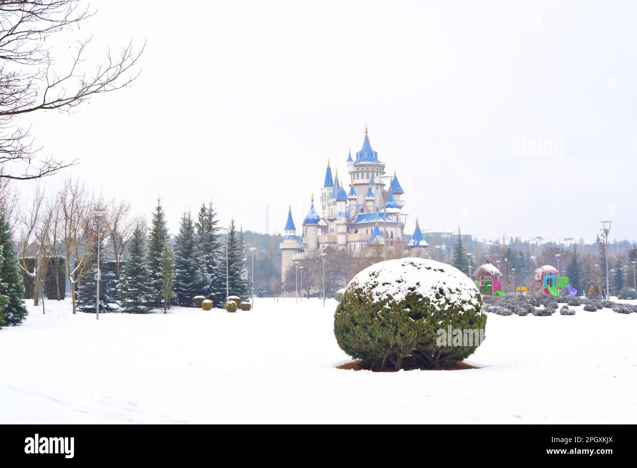 Blue vintage castle under snow behind bushes and trees in winter Stock Photo