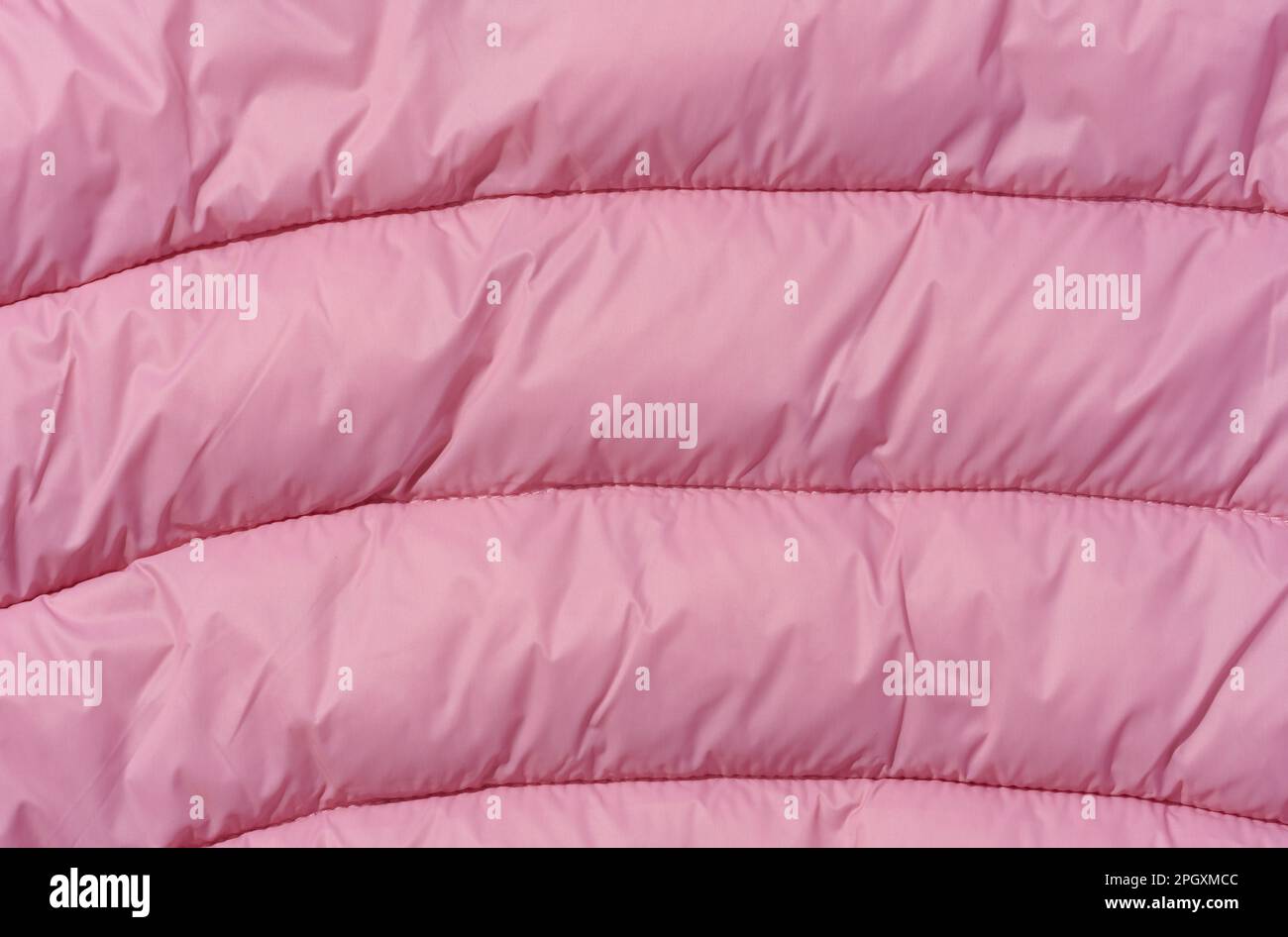 A fragment of pink fabric with down filling and stitching, fabric for jackets and coats Stock Photo