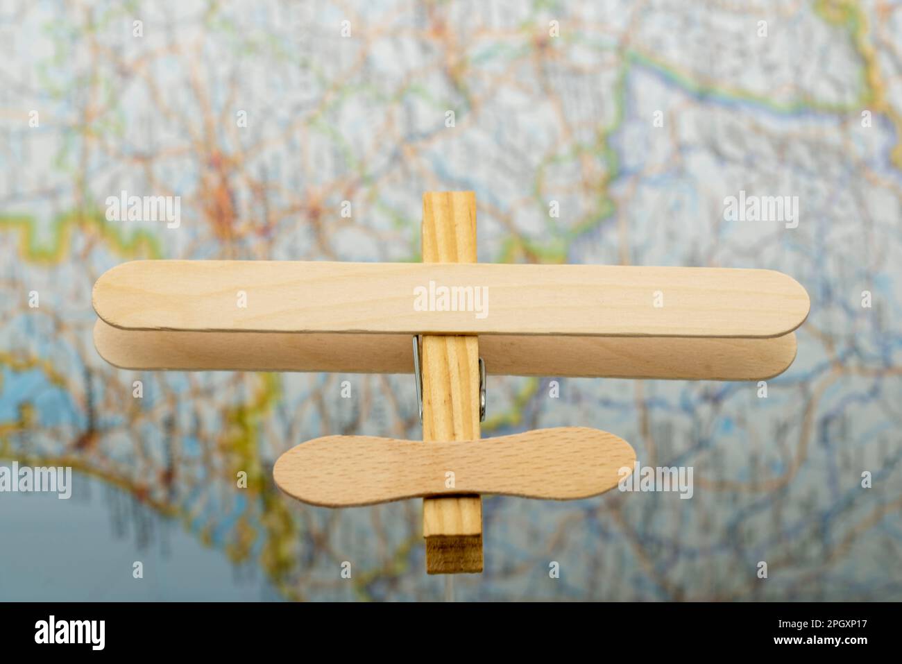 Avión de madera hecho con palos de helado y una pinza de la ropa, volando sobre un mapa Stock Photo