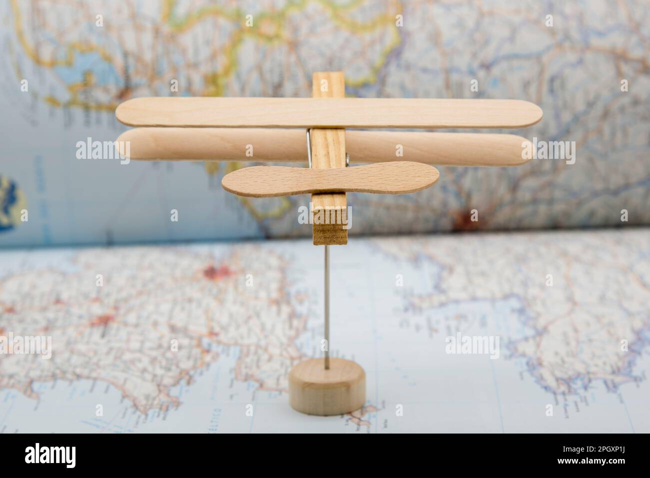 Avión de madera hecho con palos de helado y una pinza de la ropa, volando sobre un mapa Stock Photo
