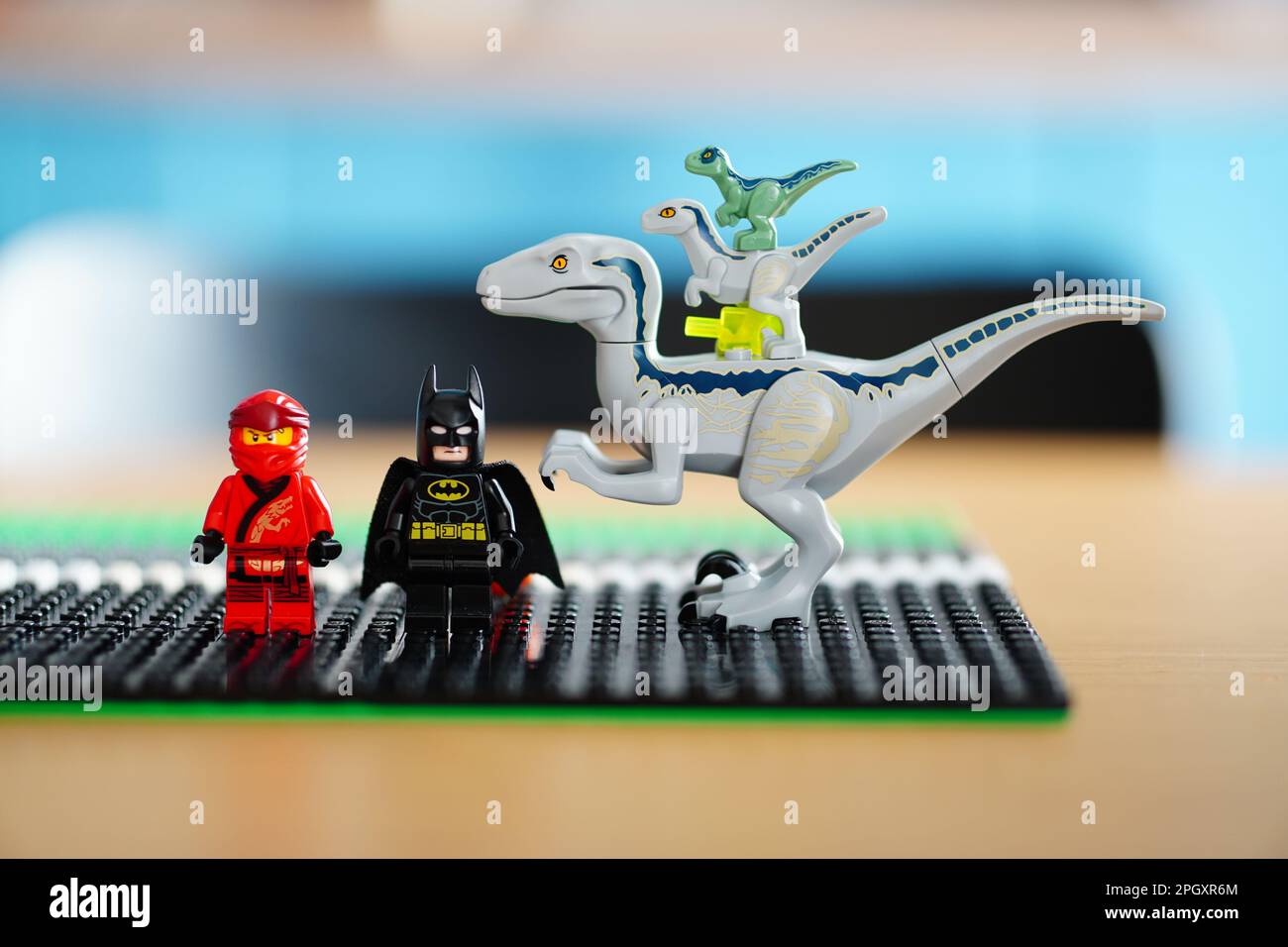 Two Lego figures sit side-by-side with a small white dinosaur, enjoying a moment of companionship Stock Photo