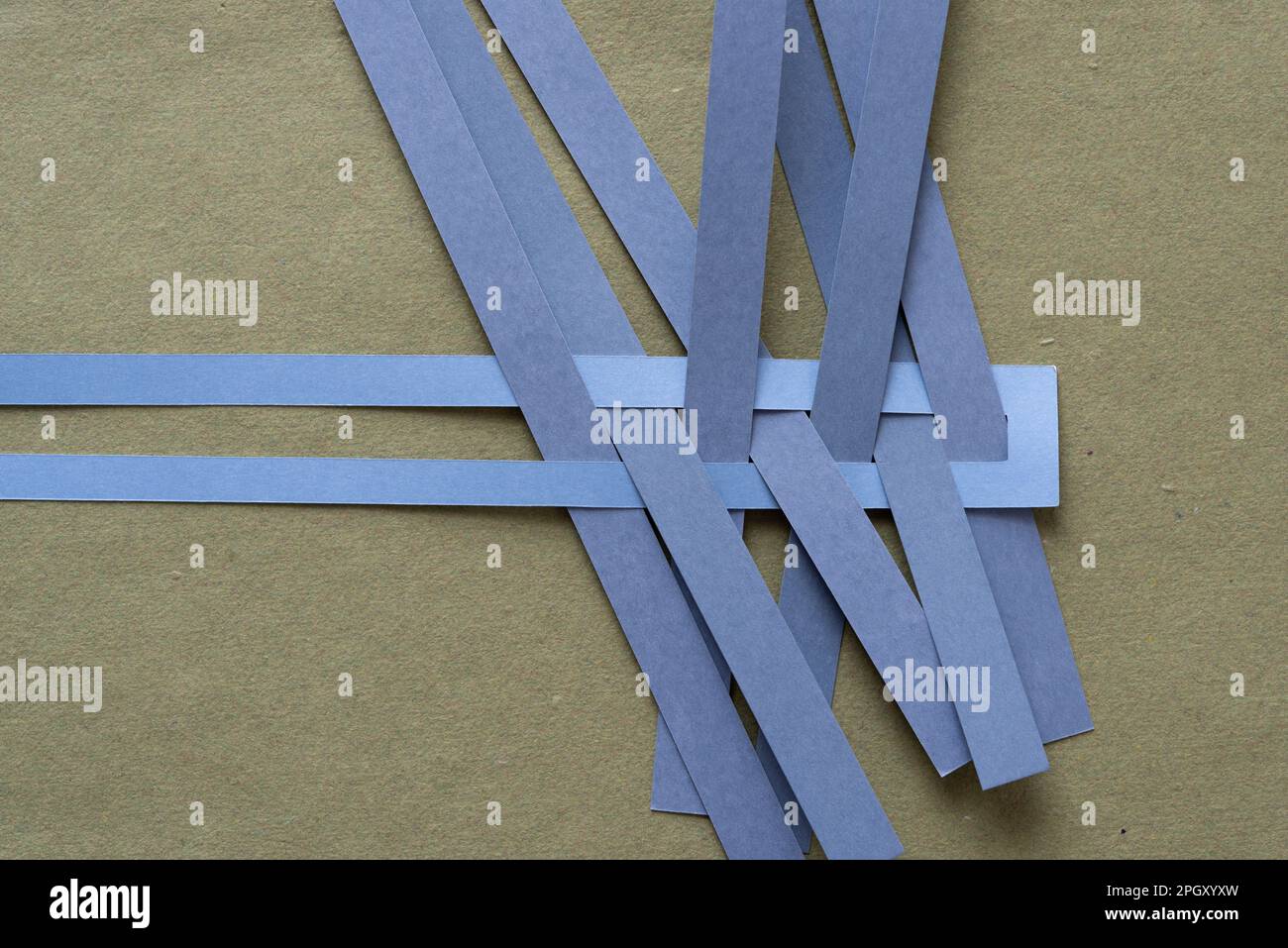 thin paper stripes in blue gray intersecting a paper frame on rough