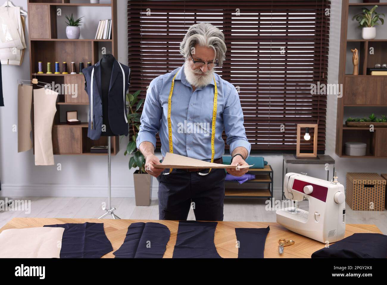 Professional tailor with sketch near table in workshop Stock Photo