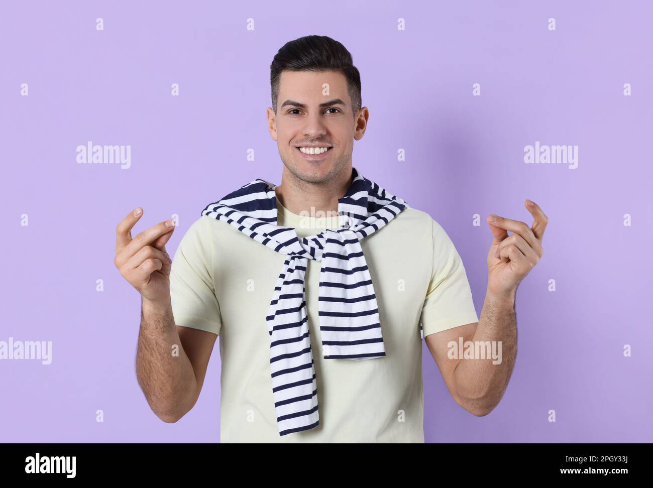 Handsome man snapping fingers on violet background Stock Photo